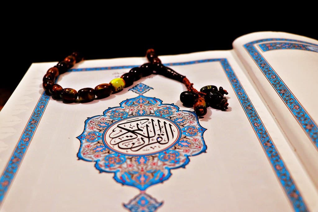 Prayer beads resting on the illuminated opening page of a Quran